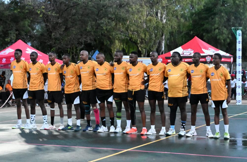 Netball team in orange kit lined up on the court